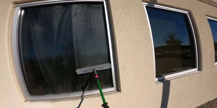Technician using a water-fed pole to clean second-story windows on a San Clemente home