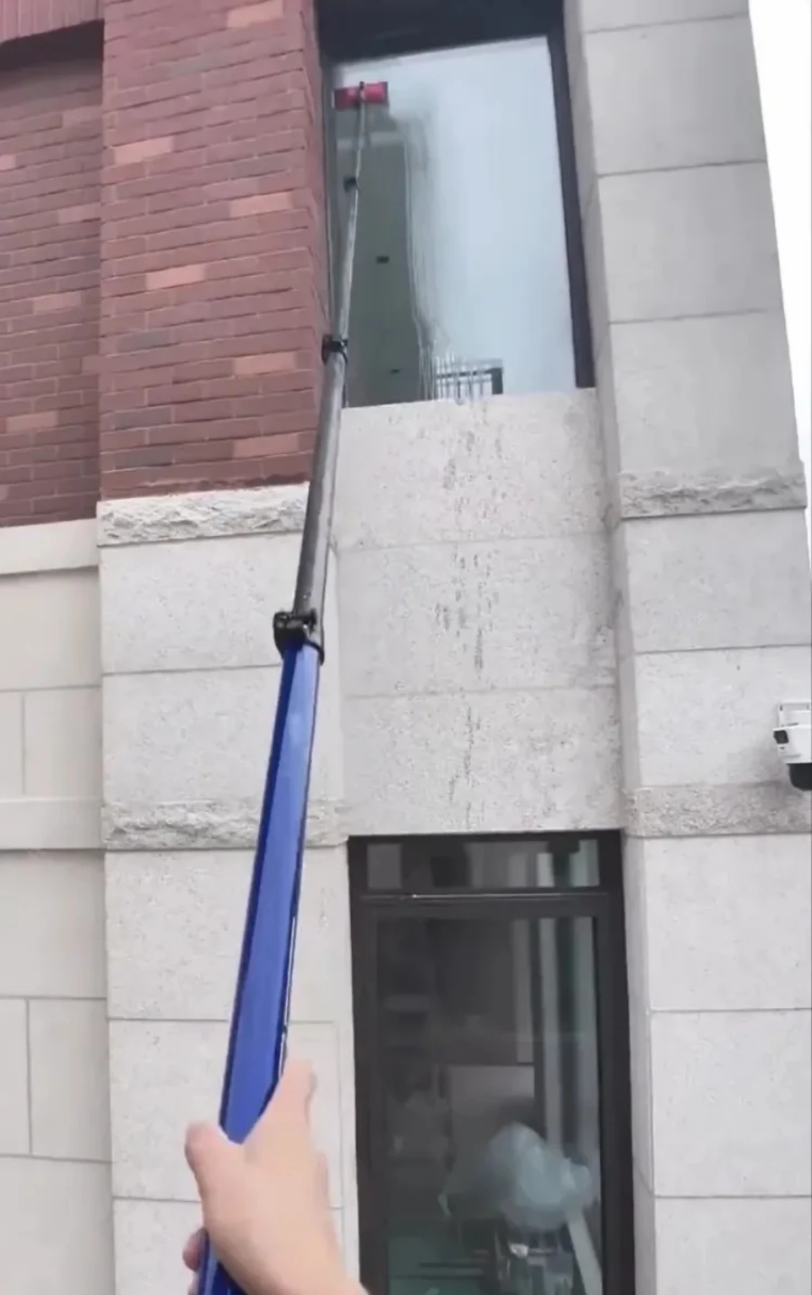 Technician using a water-fed pole system to clean an upper-story window in San Clemente, CA