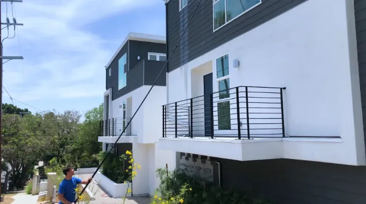 Window washing San Clemente CA technician using a water-fed pole on a residential home